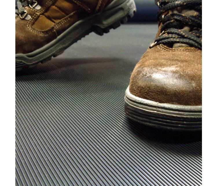 Work boots stepping onto black ribbed Duragrip rubber matting